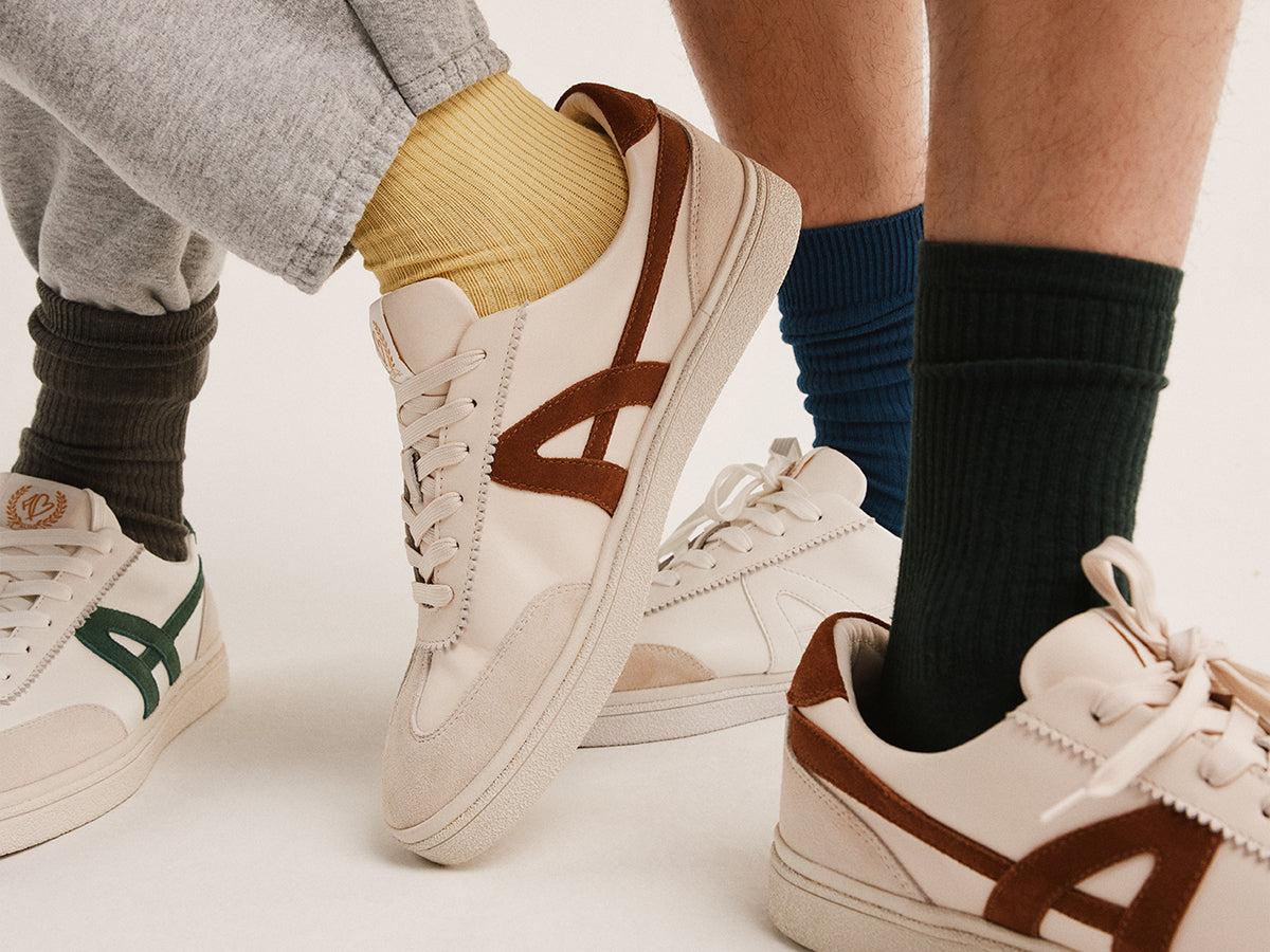 Four pairs of sneakers worn by different people on a white background
