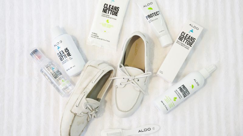 White boat shoes are displayed surrounded by shoe cleaning products on a striped background.