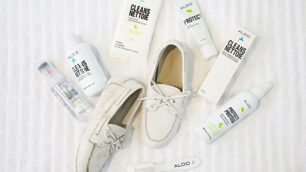 White boat shoes are displayed surrounded by shoe cleaning products on a striped background.