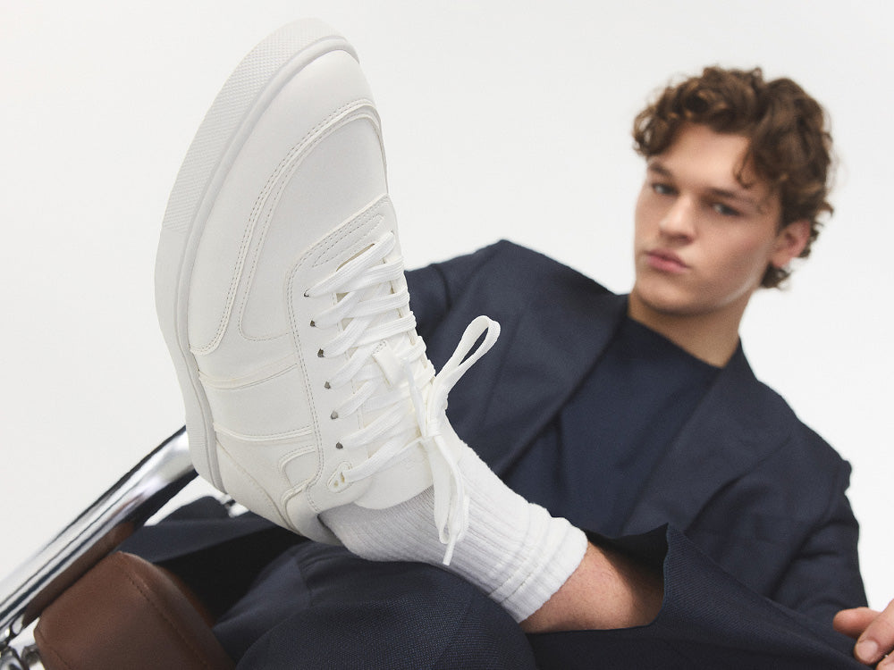 A man wearing a blue suit paired with white sneakers.